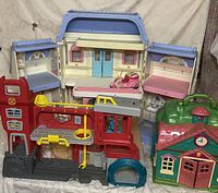 Full view showing all three main playsets: Strawberry Shortcake playhouse, Transformer Base, and Fisher-Price house with handle.