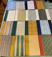 Top down photo showing all 25 vintage hardback Reader's Digest books arranged in rows, displaying the variety of patterned and colored covers.