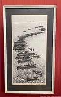 Framed monochrome woodblock print depicting boats along shoreline