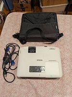 Top view of one Epson projector with cables and carrying case visible.