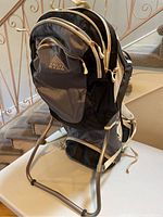 Front view of the Kelty Kids FC 3.0 hiking carrier showing the front pocket, logo, and metal frame stand.