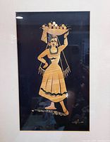 Close-up of bamboo artwork showing detailed figure of woman carrying basket of round objects on head