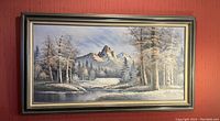 Full view of large framed oil painting showing mountain, trees, and river landscape with snow and winter colors.