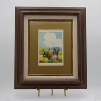 Front view of 'Llama and Lady' watercolor artwork in a wood frame with double matting showing the subject of a woman and llamas against a blue sky.