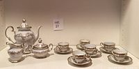 Full view of Weimar porcelain tea set including teapot, creamer, sugar bowl, 6 cups and saucers on shelf.