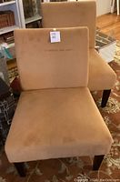 Front facing view of the two Avenue Six Laguna chairs in brushed butternut fabric showing upholstery and wooden legs.