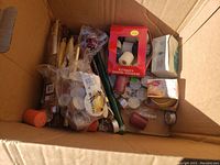 Box of assorted candles and candle holders with various sizes and colors visible, including packs, loose candles, and some new candles in packaging.