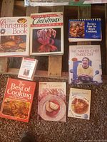 Photo showing various cookbooks arranged on a wooden surface including Christmas themed, desserts, Jamie Oliver's cookbook, diet book, and children's parties book.