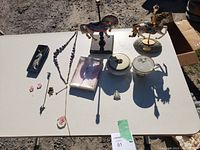 Full view of all assorted decorative items laid out on white table, showing teacups, carousel horses, and assorted jewelry pieces