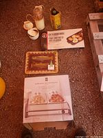 Overview showing buffet server box, cast iron griddle box, painted fish tray, veggie chopper and kitchen containers on floor