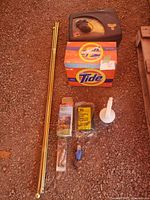 Photo of all cleaning items arranged on the ground showing Mr. Clean kit, Tide detergent, golden rods, and various other accessories.