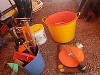 Full overview of blue bucket containing fishing rods and other gear, yellow bucket, red scoop bucket, and HT Hi-Tech tip ups on packaging.