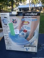 Front view of the box showing the product features of the HoMedics UltraSpa foot bubbler with pedicure center and heat function.