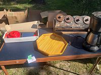 Mandoline slicer, vintage kitchen jars on wooden rack, bamboo serving tray, coffee maker on table outdoors