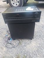 Front view of Onkyo AV receiver on top of subwoofer with cables visible on the ground.