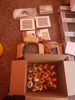 Wide view of multiple boxes and rolls of nails with ceramic corner shelves visible in background.