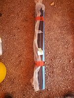 Blue under floor heating distributors bundled together, wrapped in plastic and secured with red straps on a dirt floor