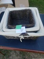 Three nesting wicker baskets stacked inside one another showing fabric liners and ties