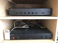 Adcom GFS-6 speaker selector unit positioned on upper shelf with six black push buttons and power LED indicator.