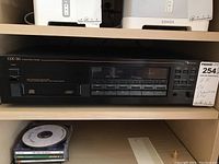 Front view of the Nakamichi CDC-3A showing disc tray, buttons, and included CD discs below.