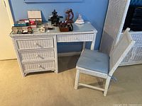 Desk and chair set in white wicker with glass top desk and drawers, chair with cushion.