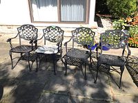 Four cast aluminum chairs arranged on stone patio in front of sliding door
