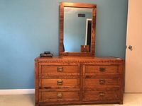 Front view of oak dresser with six drawers and brass pull handles under a mounted mirror