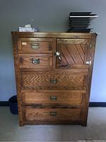 Front view of oak wood dresser showing five drawers and cupboard door with brass hardware and broken latch.