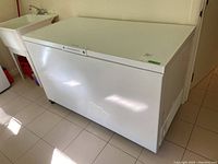Front view of white Frigidaire chest freezer on casters in utility room