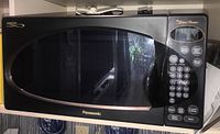 Full front view of Panasonic black microwave with large glass door and keypad on right