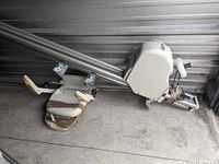 Full view of Acorn Superglide 130 stair lift showing padded seat, armrests, and metal track with mounting brackets.