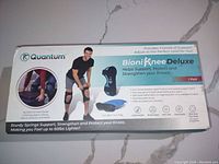 Top side of box showing product name, images of knee brace worn, and included items (2 braces, carrying bag, instructions).