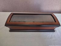 Closed wooden watch display box with curved glass top