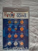 Front view of sealed plastic plaque labeled Disney Epcot International Coins showing 14 different international coins mounted inside with country names