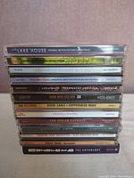 Stack of 13 music CDs showing titles and condition of jewel cases.