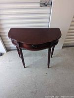 Front view of small console table showing curved front edge and turned legs