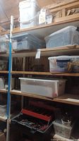 Shelving unit with multiple plastic bins and containers holding various hardware and metal repair parts arranged on wooden shelves.