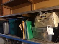 Shelf with multiple plastic storage bins and hanging file folders in various colors.