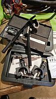 Overview of measuring tools set including digital caliper, micrometers, black metal tool, and ruler in a storage case