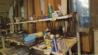 Overview of woodworking clamps on wooden shelves with various household chemical spray cans and other small containers in foreground