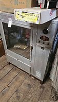 Full view of the vintage Barbecue King smoker showing the glass front door, metal body, and worn condition.