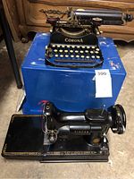 Overall view showing Singer sewing machine in front and Corona typewriter on blue surface