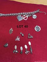 Full view of Monet marked silver tone charm bracelet with multiple charms laid on red background.