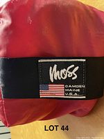 Close up of red carrying bag with Moss label showing Camden Maine USA and flag