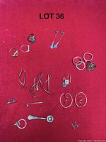 Overview of the sterling silver jewelry lot including various rings and earrings displayed on a red fabric background.