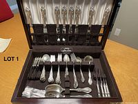 Open wooden case showing full silver service set, knives in top rack and other pieces in bottom