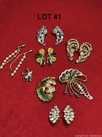 Full view of various costume jewelry including several earrings pairs and pins on red background