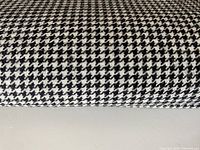 Close-up of folded black and white small houndstooth check wool fabric showing texture and pattern detail