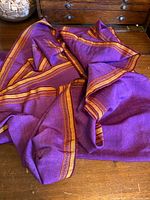 Photo showing the fuchsia fabric draped with visible tangerine borders on both sides, highlighting texture and color.