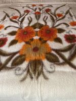 Close-up of the hand dyed floral design in warm autumn colors on the thick wool surface.